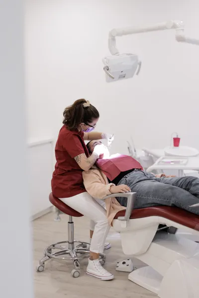 Hygiéniste dentaire (moi) en train d'effectuer un détartrage sur une patiente installée dans un fauteuil dentaire